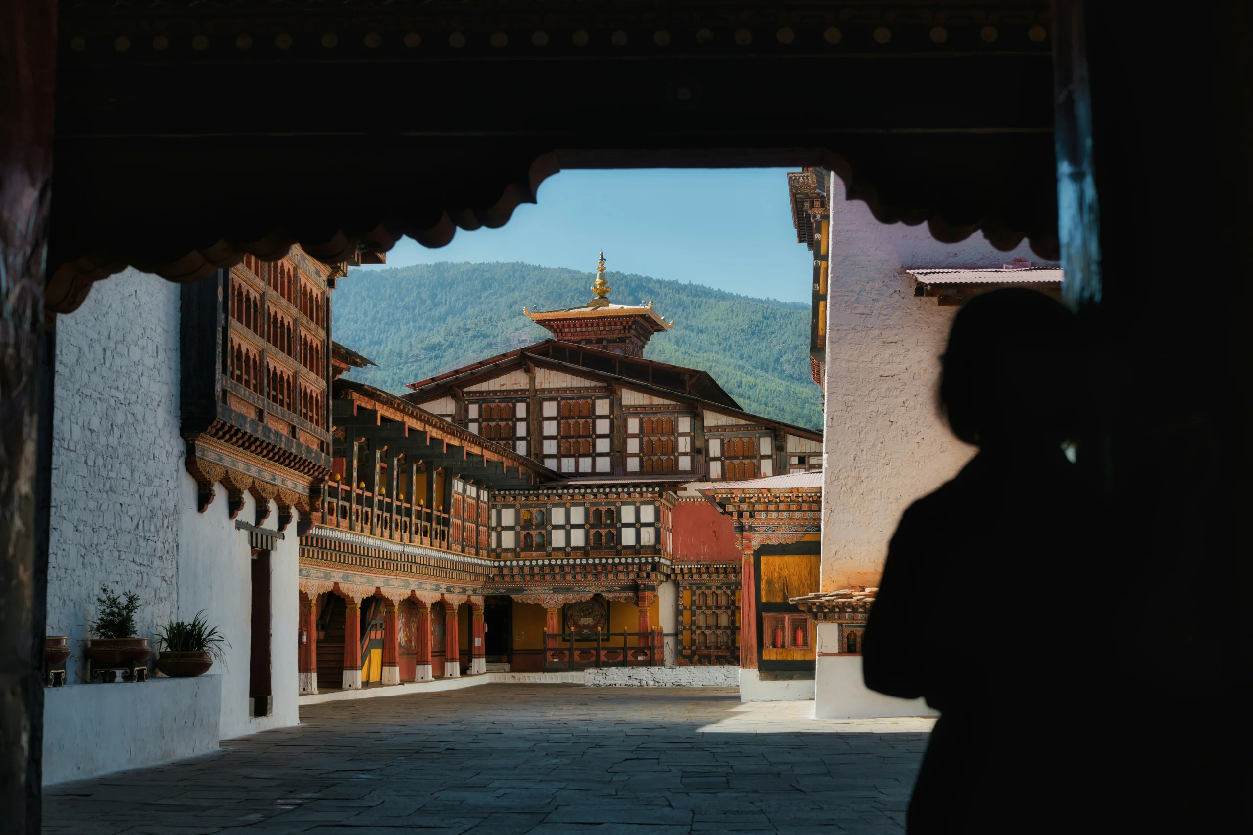 A lone monk crossing a mist-covered dzong courtyard at dawn